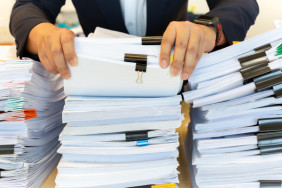 businessman-in-suit-look-through-pile-of-documents-in-office_42667-873
